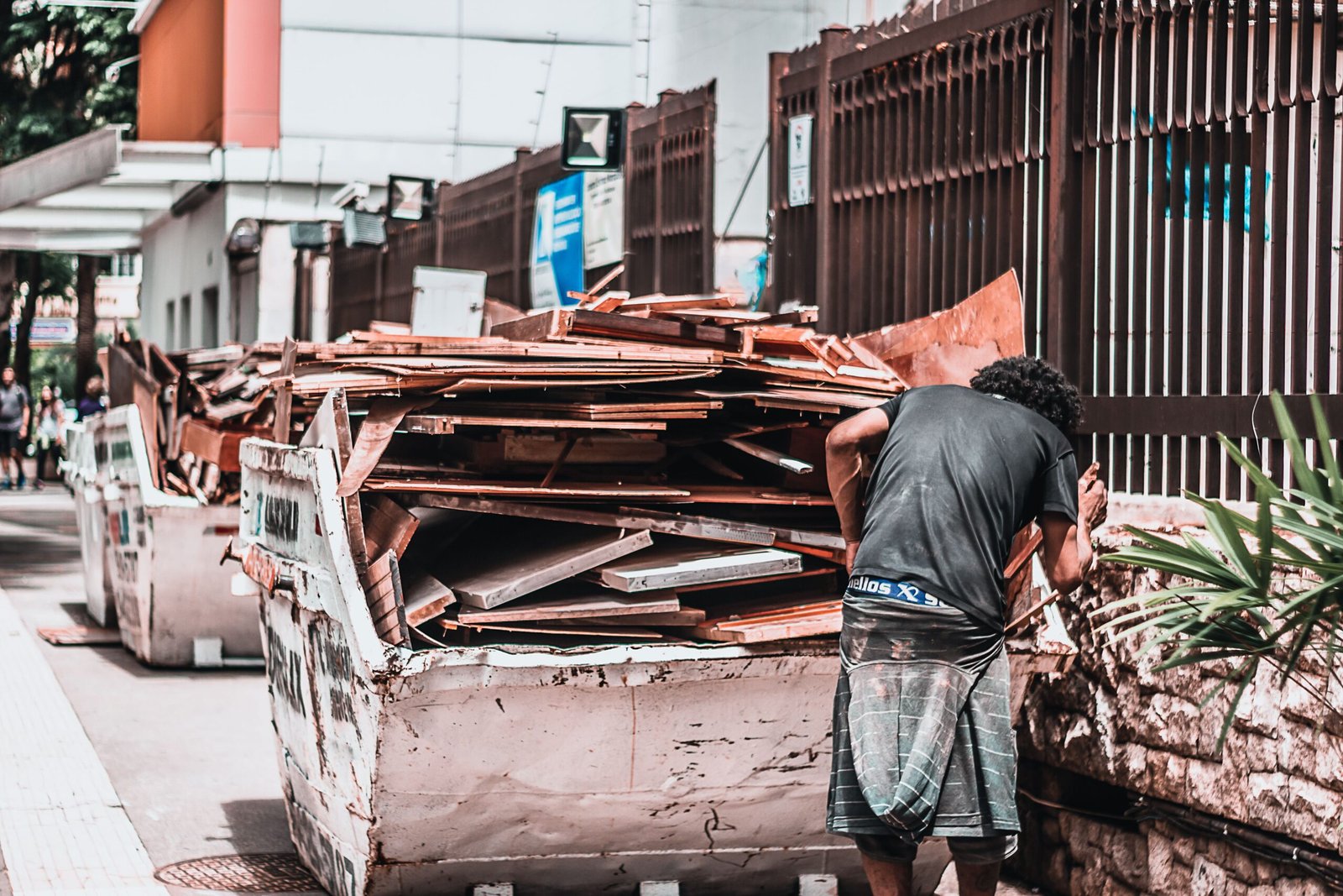 Worker beside a skip container filled with scrap timber and construction offcuts